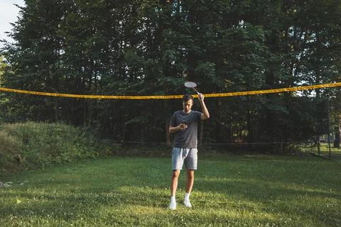 Addicted to the mobile phone even when playing badminton. A black-haired man  Foto stock