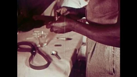 Addicts are shown preparing heroin injections in this 1951 drug prevention film. Video stock 106906419