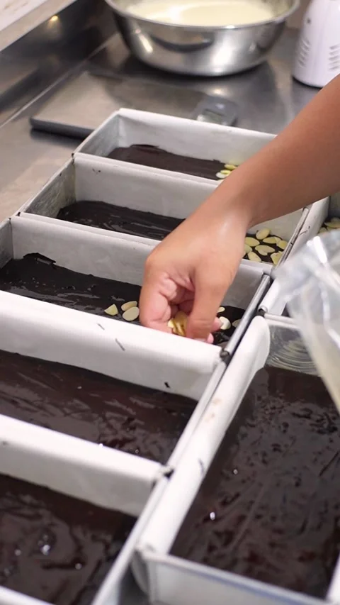 Adding almond slices topping on chocolate brownie batter in baking tray, cl.. 库存影片 331297258