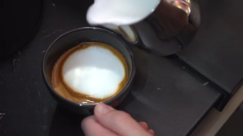 Adding and mixing milk froth and cappuccino coffee in a cup Stock Footage 117977025