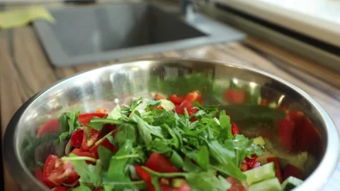 Adding arugula to a fresh vegetable salad Stock Footage 134075109