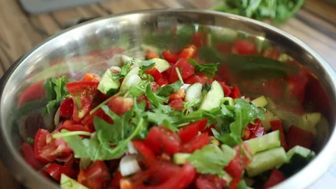 Adding arugula to a fresh vegetable salad Stock Footage 134075110