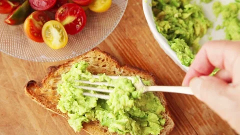 Adding bacon and cherry tomatoes to avocado toast Stock Footage 93790520