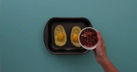 Adding bacon bits to eggs, cheese, in a potato halves 1 Stock Footage 132149122