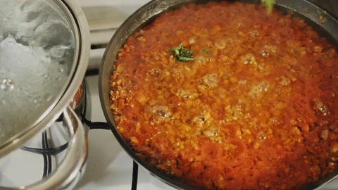 Adding basil and parsley in a pan with bolognese sauce Stock Footage 124419021