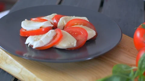 Adding basil to the Caprese  Salad. Black background Stockbeeldmateriaal 109269122