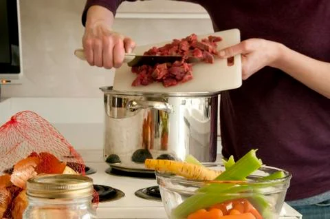 Adding Beef with cutting board to soup pot Stock Photos