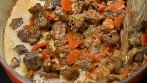 Adding beer to meat, carrot, fried tomato, onion and garlic Stock Footage 221355563
