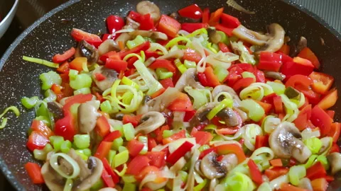 Adding black pepper to food. Various vegetables are frying in a pan Stock-Footage 301237891
