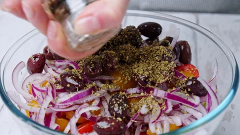 Adding black pepper into a Greek Salad. Concept of sprinkling spices into salad Stock Footage 142115532