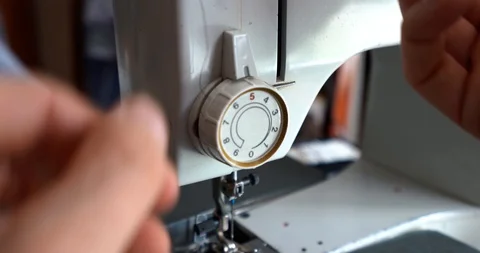 Adding a black thread to a white sewing machine, close up Stock Footage 129353885