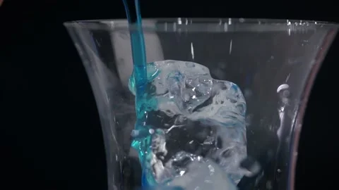 Adding blue curacao syrup to a glass with ice. Making a blue lagoon cocktail Stock Footage 219564550
