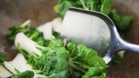 Adding bok choy to wok to stir fry Stock Footage 98519471