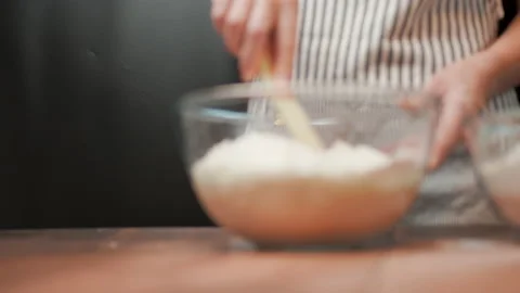 Adding in a bowl and mixing Ingredients for pizza dough on a wooden table in 4K. Stock Footage 137426112