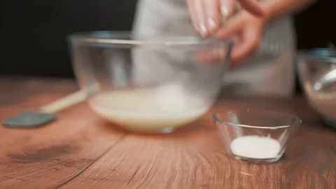 Adding in a bowl and mixing Ingredients for pizza dough on a wooden table in 4K. Stock Footage 137426188