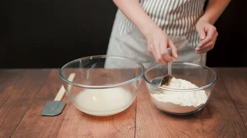 Adding in a bowl and mixing Ingredients for pizza dough on a wooden table in 4K. Stock Footage 137426199