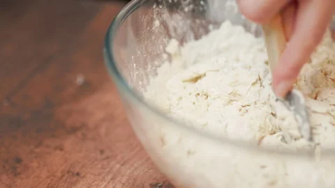 Adding in a bowl and mixing Ingredients for pizza dough on a wooden table in 4K. Stock Footage 137426384