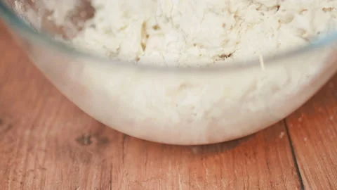 Adding in a bowl and mixing Ingredients for pizza dough on a wooden table in 4K. Stock Footage 137427037