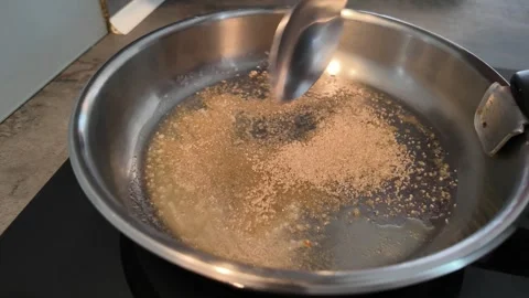 Adding brown sugar to pan for homemade caramel Stock-Footage 347011931