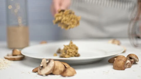 Adding a bunch of mushroom risotto with a wooden spoon in a white serving plate. Stock Footage 134697804