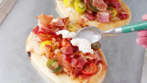 Adding burrata cheese to bacon and tomato pizzas Stock Footage 91447736