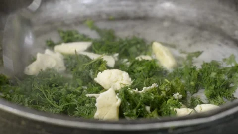 Adding butter to frying springtime fresh dill plants inside pan Stock Footage 131196491