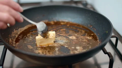 Adding butter into a hot pan and melting it with a spoon in 4K in slow-motion. Stock Footage 138286225