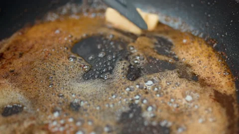 Adding butter into a hot pan and melting it with a spoon in 4K in slow-motion. Stock Footage 138286325