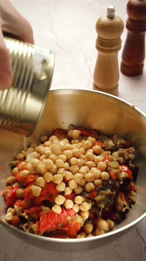 Adding canned chickpeas into a bowl with chopped vegetables Stock Footage 327905270