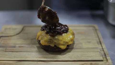 Adding Caramelized Onion Sauce Into Cheeseburguer made with Cheddar Cheese Stock Footage 129032274