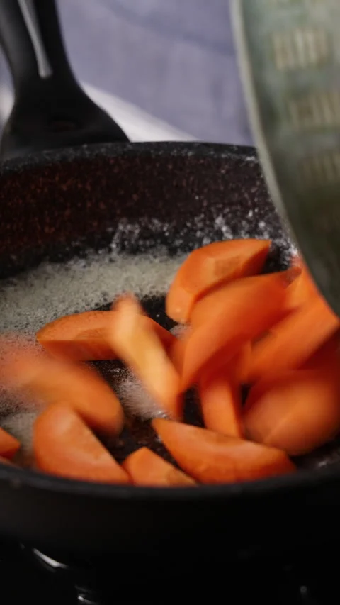Adding Carrot Half Rounds To Frying Pan Front View Close Up Vidéo 336203221