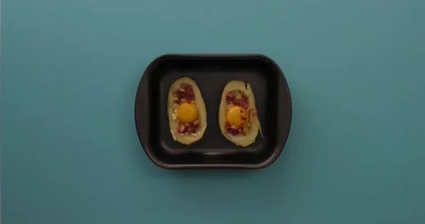 Adding cheese to bacon, eggs, and cheese in potato halves 1 Stock Footage 132149153