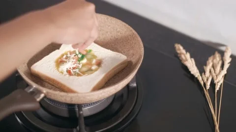Adding cheese on dough while cooking sandwich Stock Footage 205425236