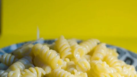 Adding a cheese to pasta in plate.,cheese falling on pasta macaroni closeup slow Vidéo 102166153