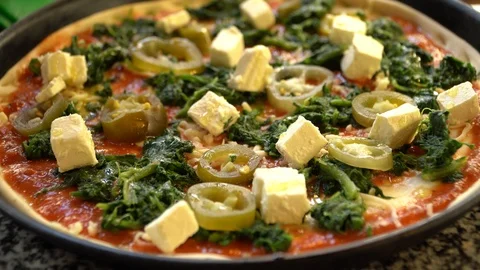 Adding cheese on pizza with spinach and feta cheese before baking Stock Footage 117415788