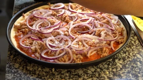 Adding cheese on pizza with tuna and onions before baking Stock Footage 117415763