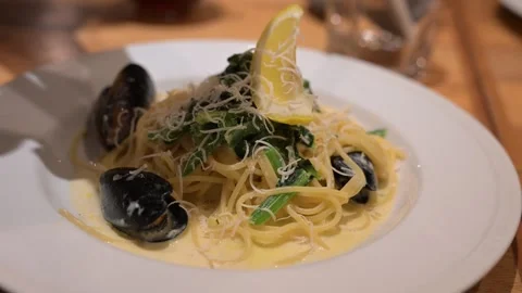 Adding cheese on spaghetti with mussels and spinach Видео 310805341