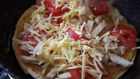 Adding cheese while preparing pizza with tomatoes on a frying pan Stock Footage 131673065
