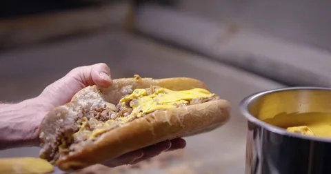 Adding cheese whiz to an authentic Philadelphia cheesesteak Vídeos de archivo 85043615
