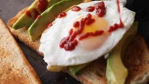 Adding chili sauce to avocado toast and egg Stock Footage 78167147