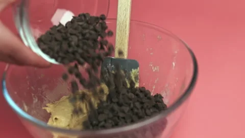 Adding Chocolate Chips into a bowl with liquid Cookies dough in 4K. Stock Footage 135701375