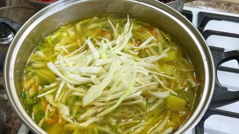 Adding chopped cabbage to a pot with potatoes and carrots.  Stock-Footage 302754793