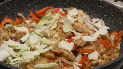 Adding chopped cabbage on top of chicken chunks roasted with peppers and onions 库存影片 290090207