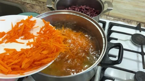 Adding chopped carrots to a pot. The process of making Ukrainian borscht. Video stock 302279609