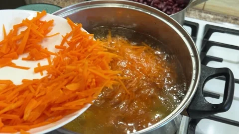 Adding chopped carrots to a pot. The process of making Ukrainian borscht. 動画素材 302754139