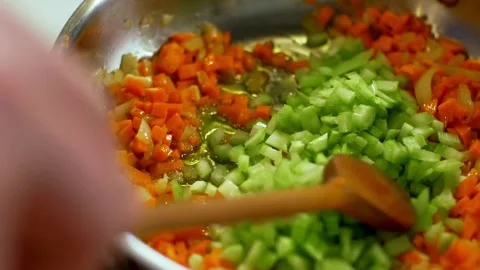 Adding chopped celery to frying carrots in a pan Vídeos de archivo 333876235