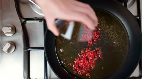 Adding chopped chili pepper into a frying pan with oil on a gas stove in 4K. Stock Footage 138408458