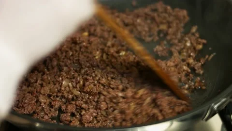 Adding chopped fresh red bell pepper to ground beef cooking on a frying pan Stock Footage 151285536