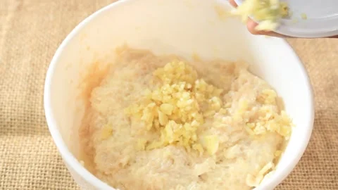 Adding chopped garlic to the dough. a bowl of dough plus chopped garlic Stock Footage 334647273