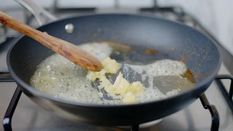 Adding chopped garlic into a preheated pan, and frying with melted cream in 4K. Stock Footage 138065561